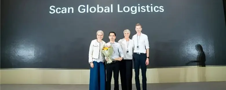 Four Scan Global Logistics colleagues on stage during a company recognition or award presentation.