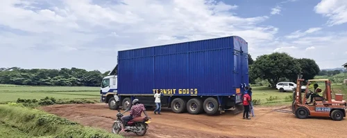 Cargo truck and forklift preparing for final-mile delivery on a rural road.