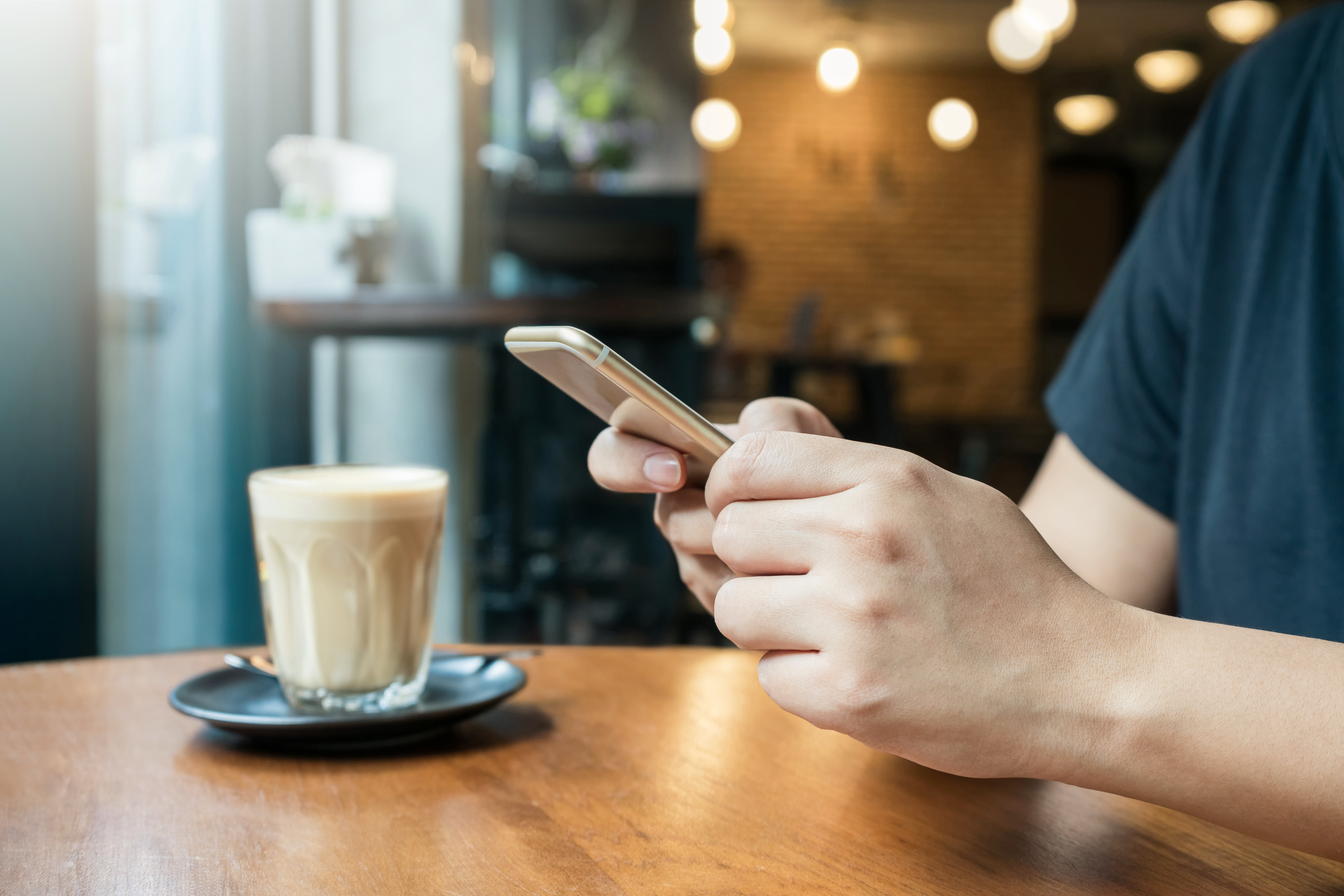 person-texting-with-latte-in-cafe