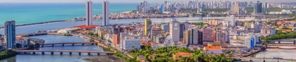 Panoramic view of Recife, Brazil, showing high-rise buildings, bridges, and waterways along the coastline