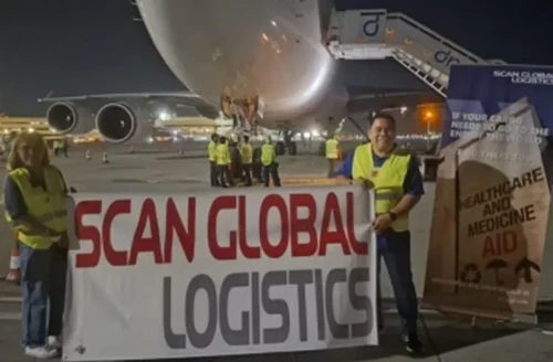 Scan Global Logistics team in front of a cargo aircraft, preparing to ship humanitarian aid during a tight emergency timeline