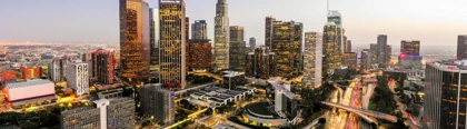 Downtown Los Angeles skyline at dusk with illuminated skyscrapers and busy highways filled with light trails