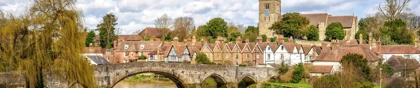 Stone bridge over the River Medway in Aylesford, Kent, with historic cottages and a church tower in the background